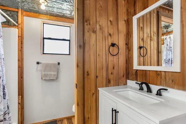 a bathroom with a granite countertop sink a mirror and shower