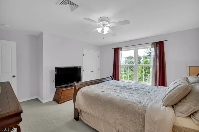 a bedroom with a bed and a flat tv screen on dresser