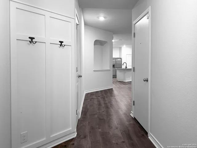 a view of a hallway with wooden floor and a bathroom