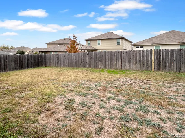 a view of a backyard with a barbeque and wooden fence