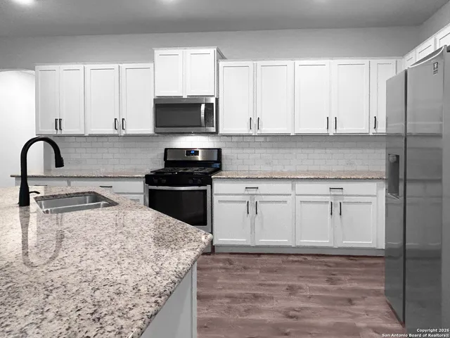 a kitchen with white cabinets and appliances