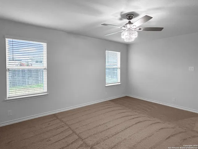 an empty room with windows and chandelier fan