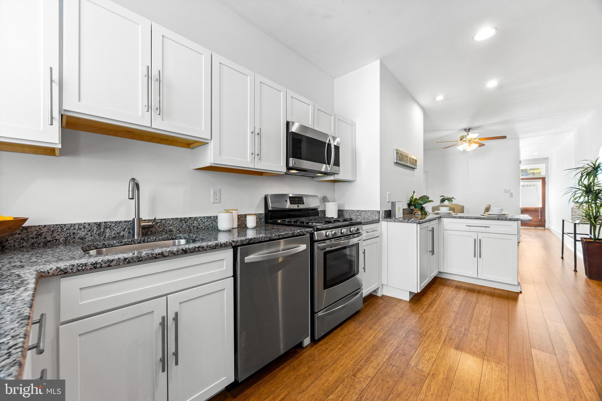 3353 Beech Avenue Baltimore, MD 21211 - Photo 15 of 32 a kitchen with granite countertop wooden floors stainless steel appliances and white cabinets