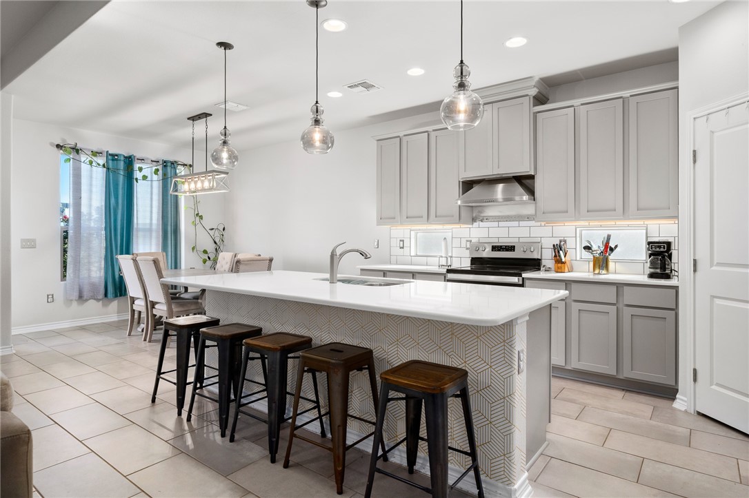 1031 Ocean Breeze Portland, TX 78374 - Photo 8 of 35 a kitchen with stainless steel appliances kitchen island granite countertop a sink a stove a refrigerator and island with wooden floor