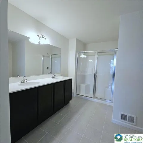 a bathroom with a double vanity sink mirror and shower