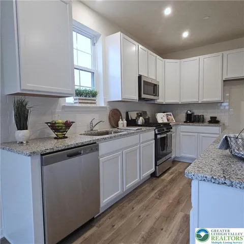 a kitchen with granite countertop a sink stainless steel appliances and cabinets