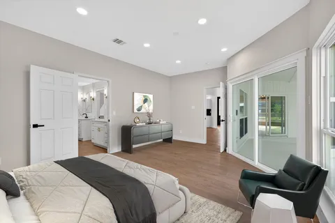 a view of an empty room with wooden floor and a bathroom
