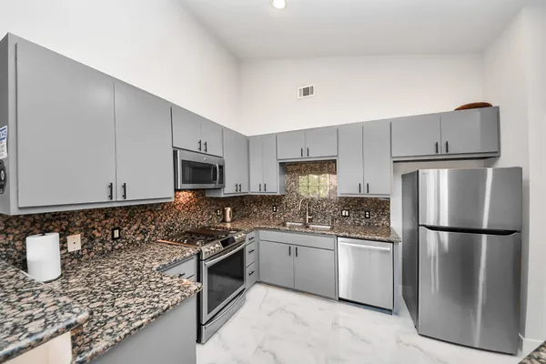 a kitchen with stainless steel appliances granite countertop a refrigerator sink and stove