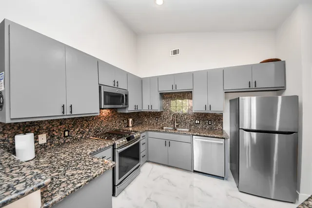 a kitchen with stainless steel appliances granite countertop a refrigerator sink and stove