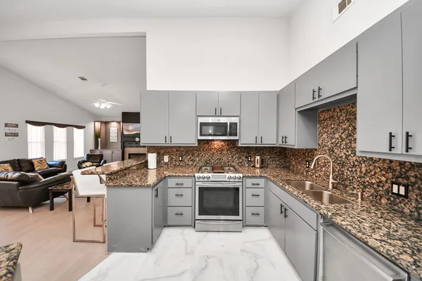 a kitchen with stainless steel appliances granite countertop a sink stove refrigerator and cabinets