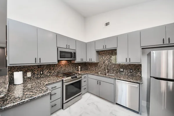 a kitchen with stainless steel appliances granite countertop a stove a sink and a refrigerator