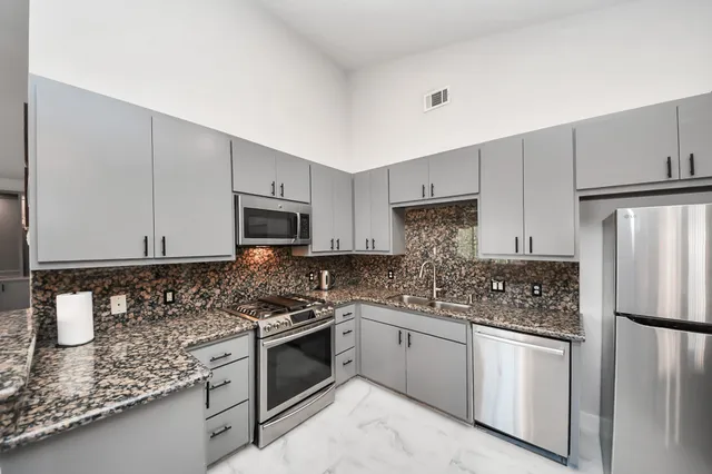 a kitchen with stainless steel appliances granite countertop a stove a sink and a refrigerator