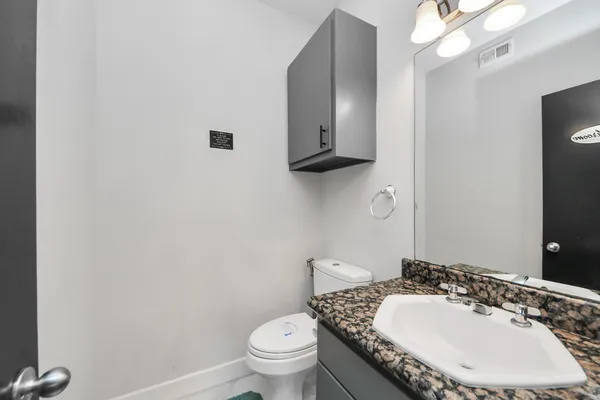 a bathroom with a granite countertop toilet a sink and mirror