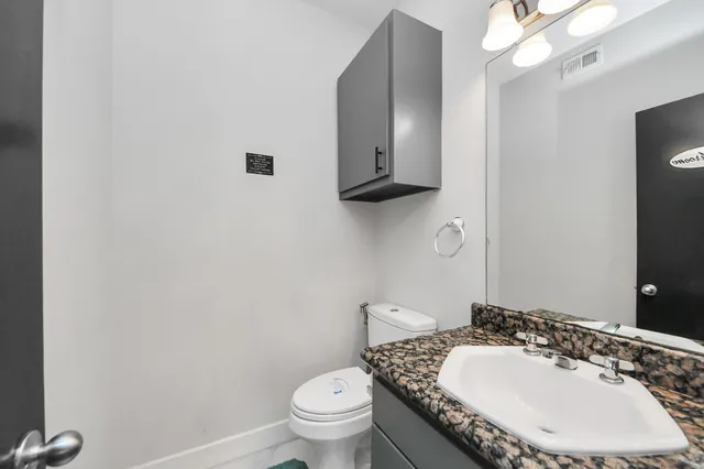 a bathroom with a granite countertop toilet a sink and mirror