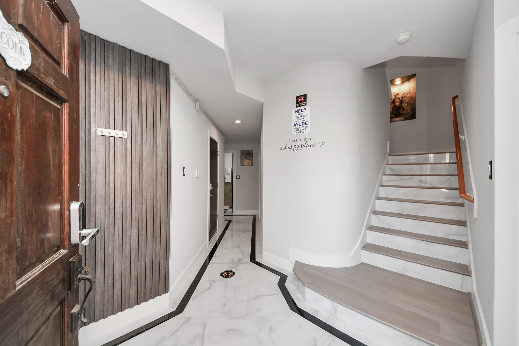 9715 Riddlewood Lane Houston, TX 77025 - Photo 3 of 43 Welcome to a stylish entryway featuring sleek marble floors, modern wood accents, and a charming staircase leading to the upper level.
