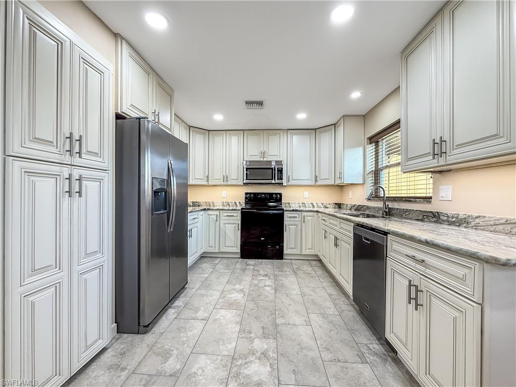 2115 St Croix Avenue Fort Myers, FL 33905 - Photo 12 of 37 Kitchen featuring black appliances, recessed lighting, and light stone countertops