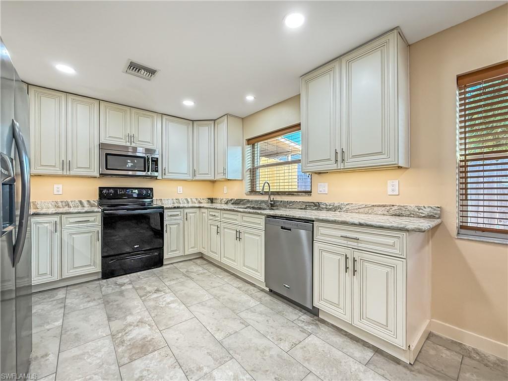 2115 St Croix Avenue Fort Myers, FL 33905 - Photo 13 of 37 Kitchen with stainless steel appliances, light stone counters, cream cabinetry, and recessed lighting