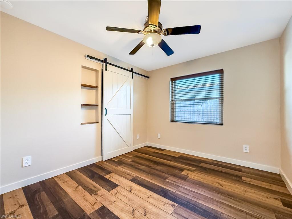2115 St Croix Avenue Fort Myers, FL 33905 - Photo 20 of 37 Unfurnished bedroom featuring a barn door, dark wood-style flooring, and ceiling fan