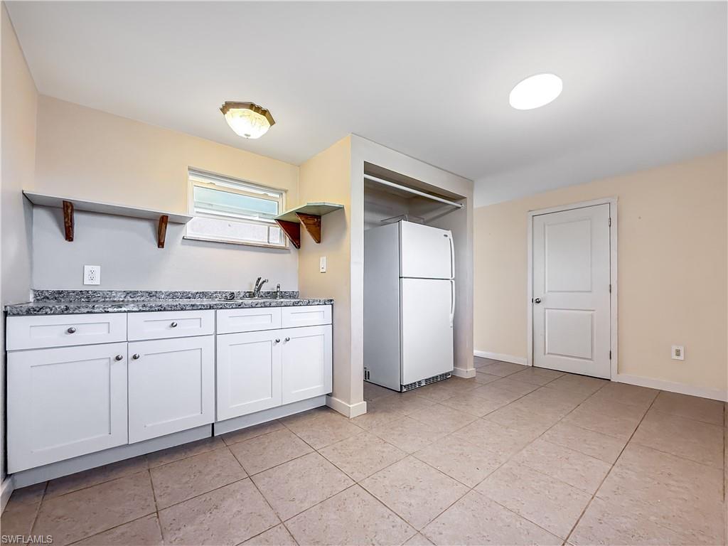2115 St Croix Avenue Fort Myers, FL 33905 - Photo 23 of 37 Kitchen featuring open shelves, freestanding refrigerator, white cabinets, light tile patterned floors, and dark stone counters