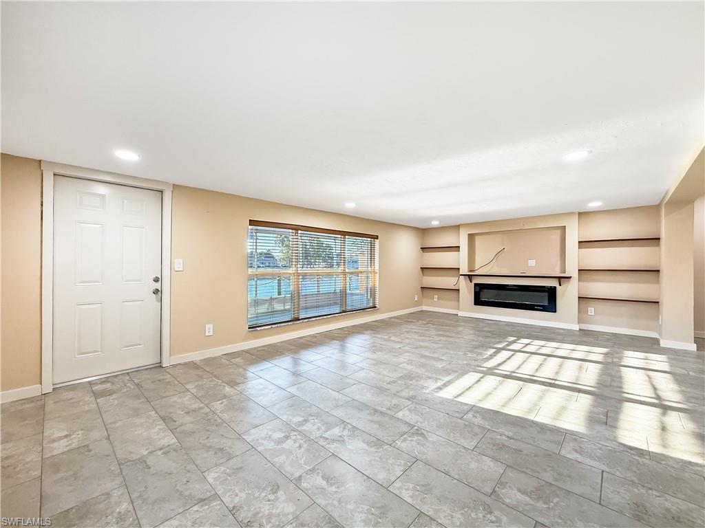 2115 St Croix Avenue Fort Myers, FL 33905 - Photo 6 of 37 Unfurnished living room with built in shelves, recessed lighting, and a glass covered fireplace