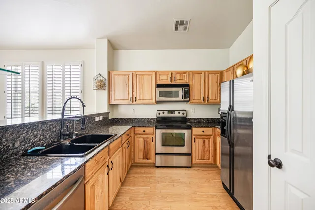 a kitchen with stainless steel appliances granite countertop a sink stove microwave and refrigerator