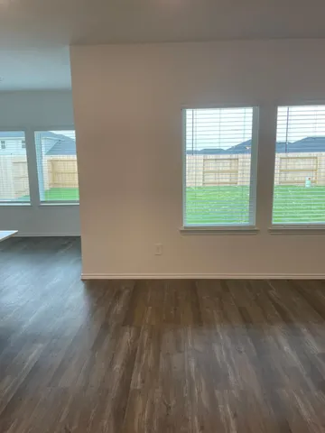 an empty room with wooden floor fan and windows