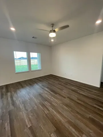 an empty room with windows and ceiling fan view