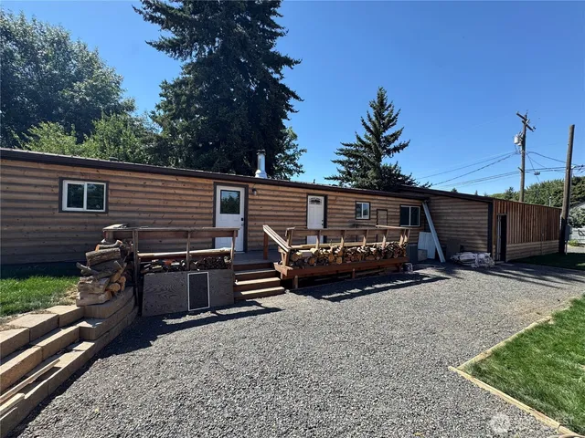 a view of a house with a yard and a wooden bench