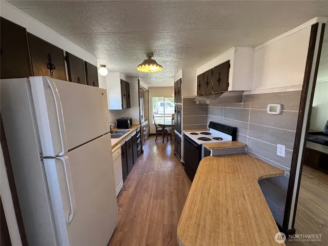 a kitchen with stainless steel appliances a refrigerator a stove a microwave a sink dishwasher and wooden floor