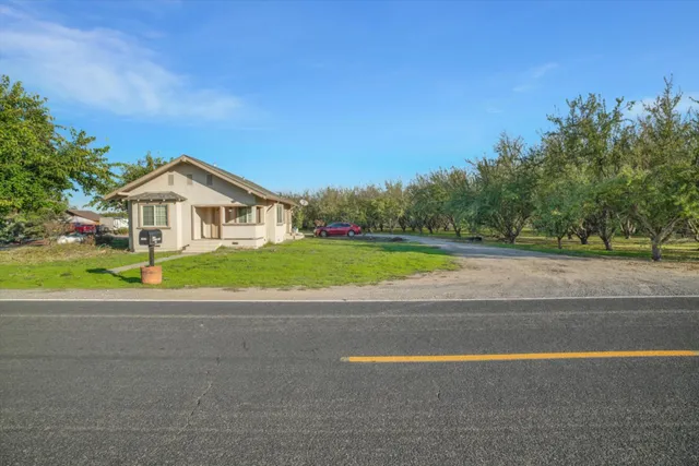 a view of big house with a yard and a large tree
