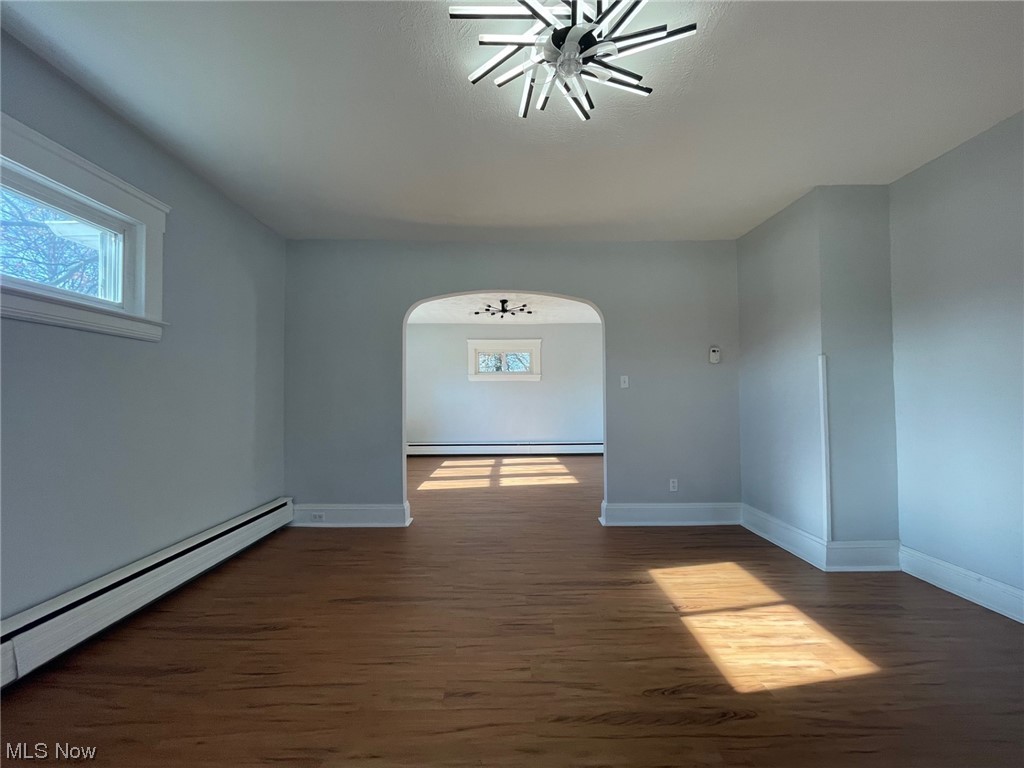 924 Richmond Road Cleveland, OH 44124 - Photo 9 of 34 Empty room featuring ceiling fan, a baseboard heating unit, and dark wood-type flooring