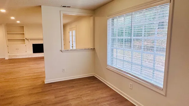 a view of an empty room with wooden floor and a window