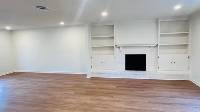 a view of empty room with wooden floor and fireplace