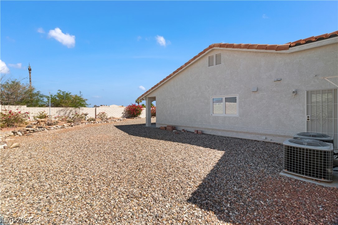 2055 Cholla Way Laughlin, NV 89029 - Photo 62 of 87 A neatly maintained backyard features a gravel expanse and vibrant landscaping along the wall.