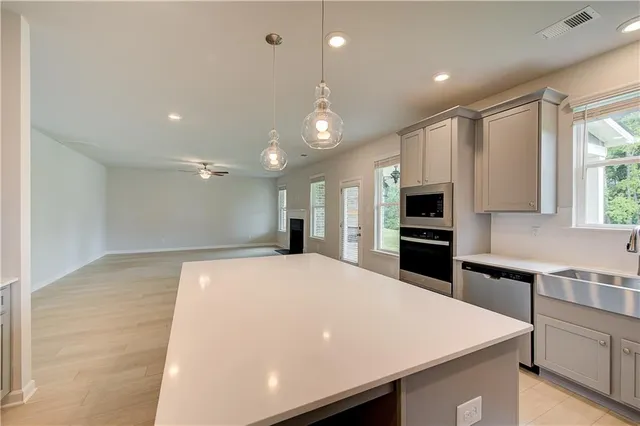 a large kitchen with kitchen island a stove a sink a oven and a refrigerator with wooden floor