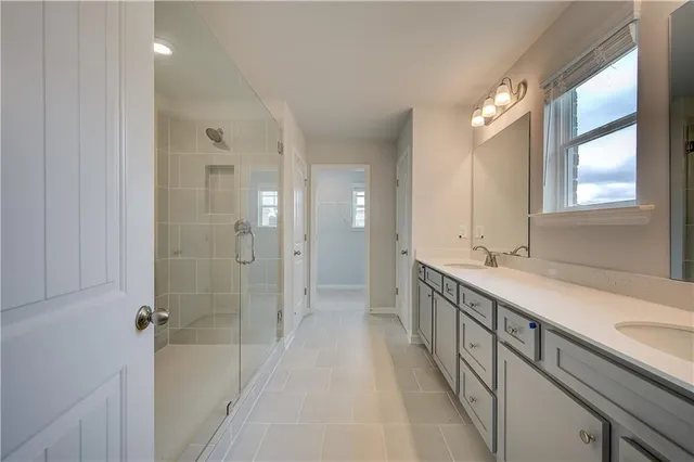 a bathroom with a double vanity sink a large mirror a shower and a bathtub