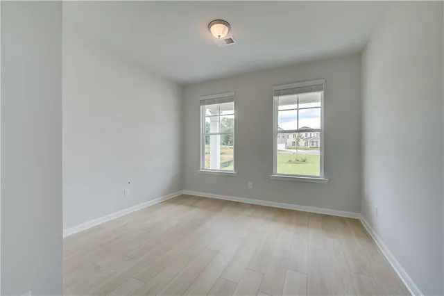 an empty room with wooden floor and windows
