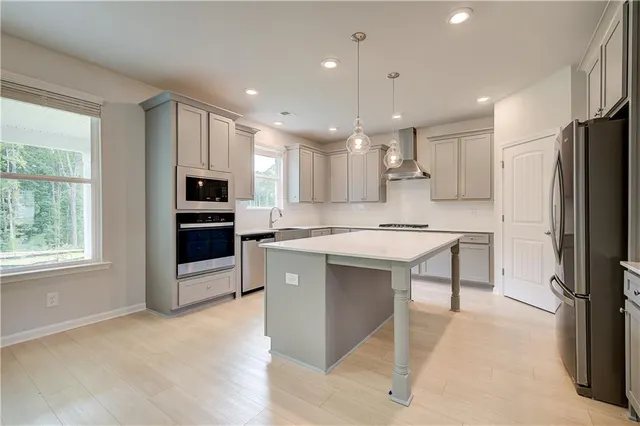 a kitchen with kitchen island granite countertop a refrigerator oven a sink dishwasher and white cabinets with wooden floor