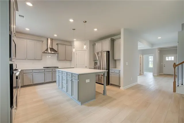 a large kitchen with a large counter top a sink stainless steel appliances and cabinets