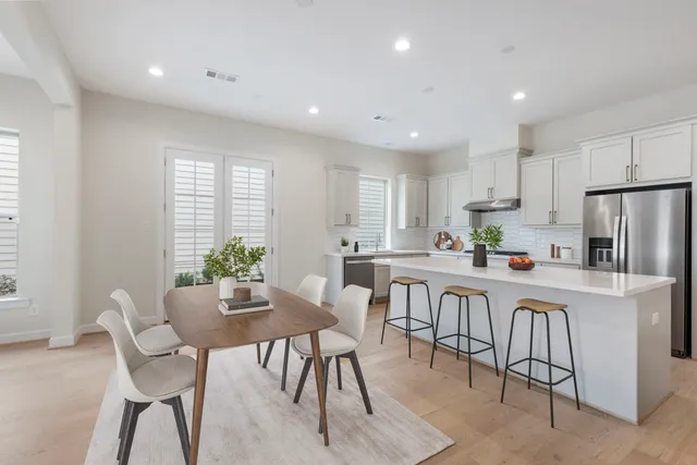 a large white kitchen with stainless steel appliances granite countertop a large counter top a stove and a refrigerator