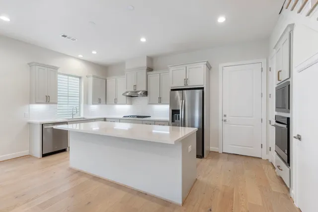 a large kitchen with kitchen island a sink stainless steel appliances and cabinets