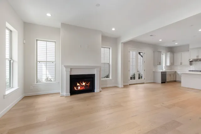a view of an empty room with wooden floor fireplace and a window