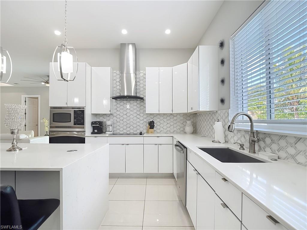 1806 41st Street Southwest Naples, FL 34116 - Photo 25 of 38 a kitchen with stainless steel appliances a sink a stove a microwave and cabinets