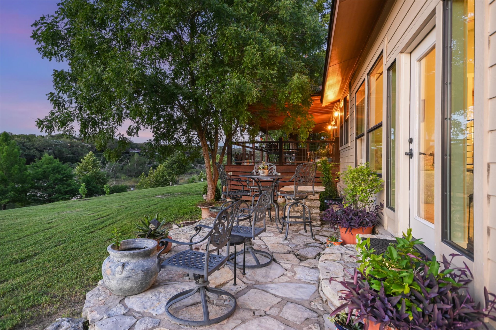 2411 Spoke Hollow Road Wimberley, TX 78676 - Photo 22 of 37 An inviting flagstone patio and elevated deck overlook a serene, treed landscape.