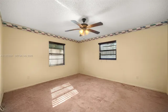 a view of a big room with windows and chandelier fan