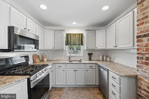 a kitchen with granite countertop a sink stove and cabinets