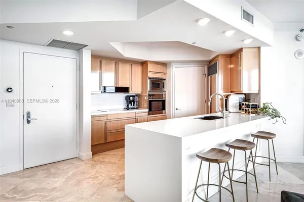 a kitchen with kitchen island a stove a sink a refrigerator and white cabinets with wooden floor