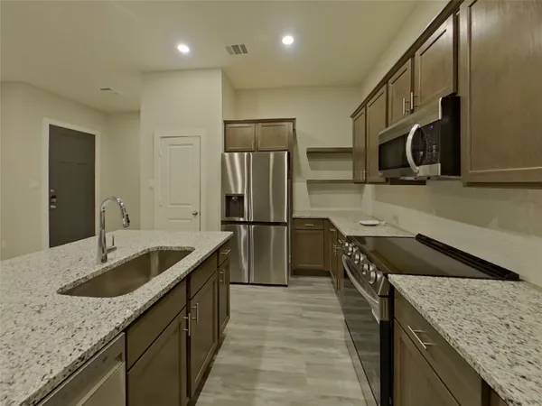 a kitchen with stainless steel appliances granite countertop a sink stove and refrigerator