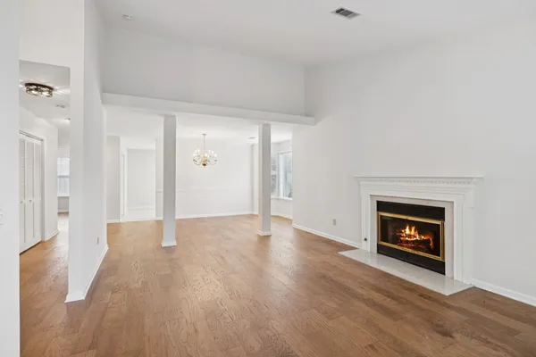 a view of an empty room with wooden floor and a fireplace