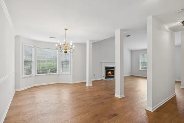 a view of an empty room with chandelier fan and fire place